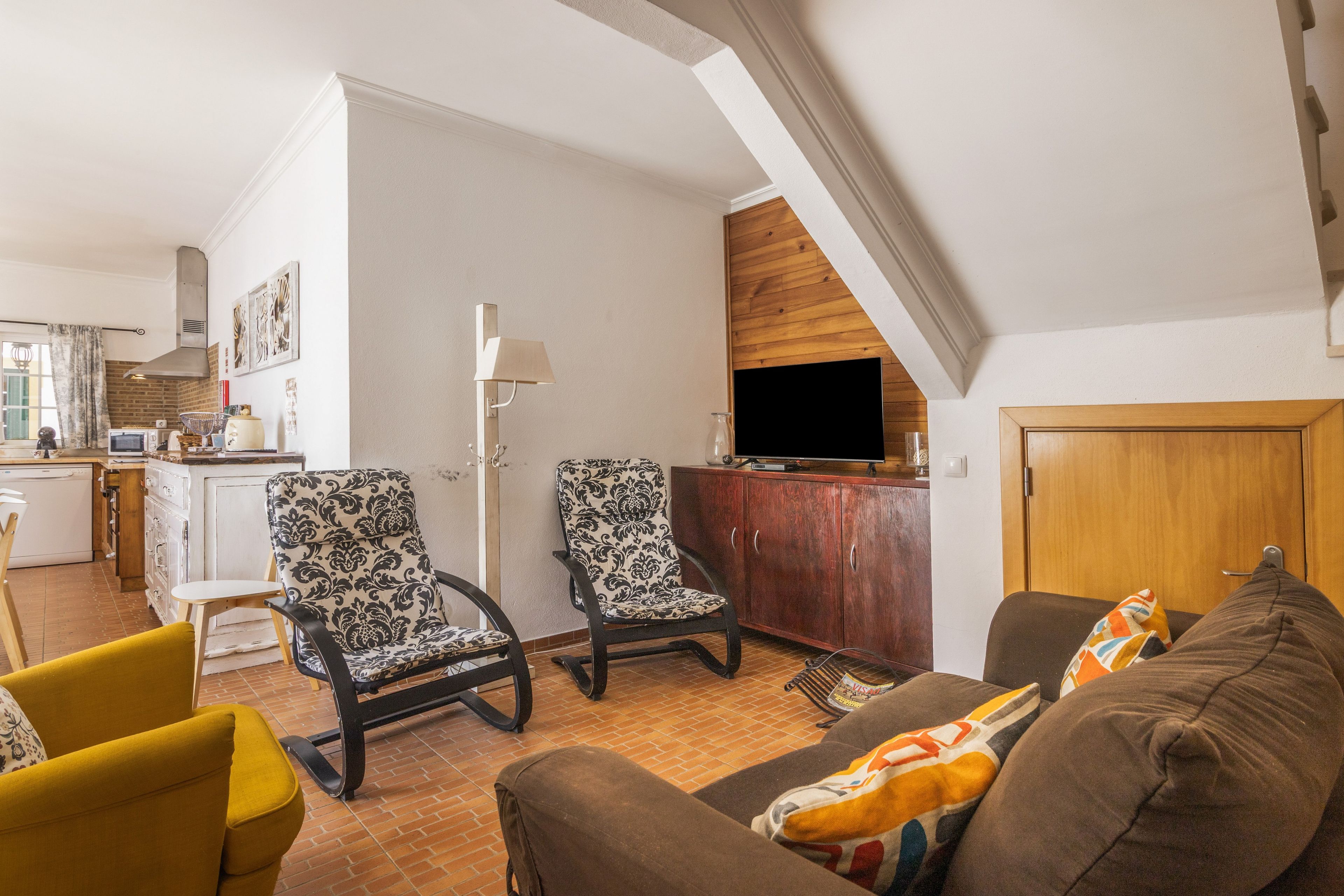 Un salon comprenant un canapé, deux fauteuils, un téléviseur et un meuble en bois.