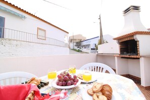 Eine Terrasse mit Frühstückstisch, mit Croissants, Trauben und Orangensaft.