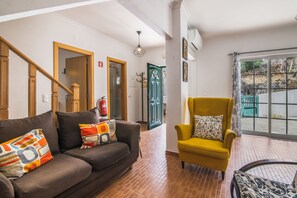 A living room with a brown sofa, a yellow armchair, and a fire extinguisher on the wall. - Villa 'Grandvale' with Private Terrace, Wi-Fi and Air Conditioning (Castro Marim)