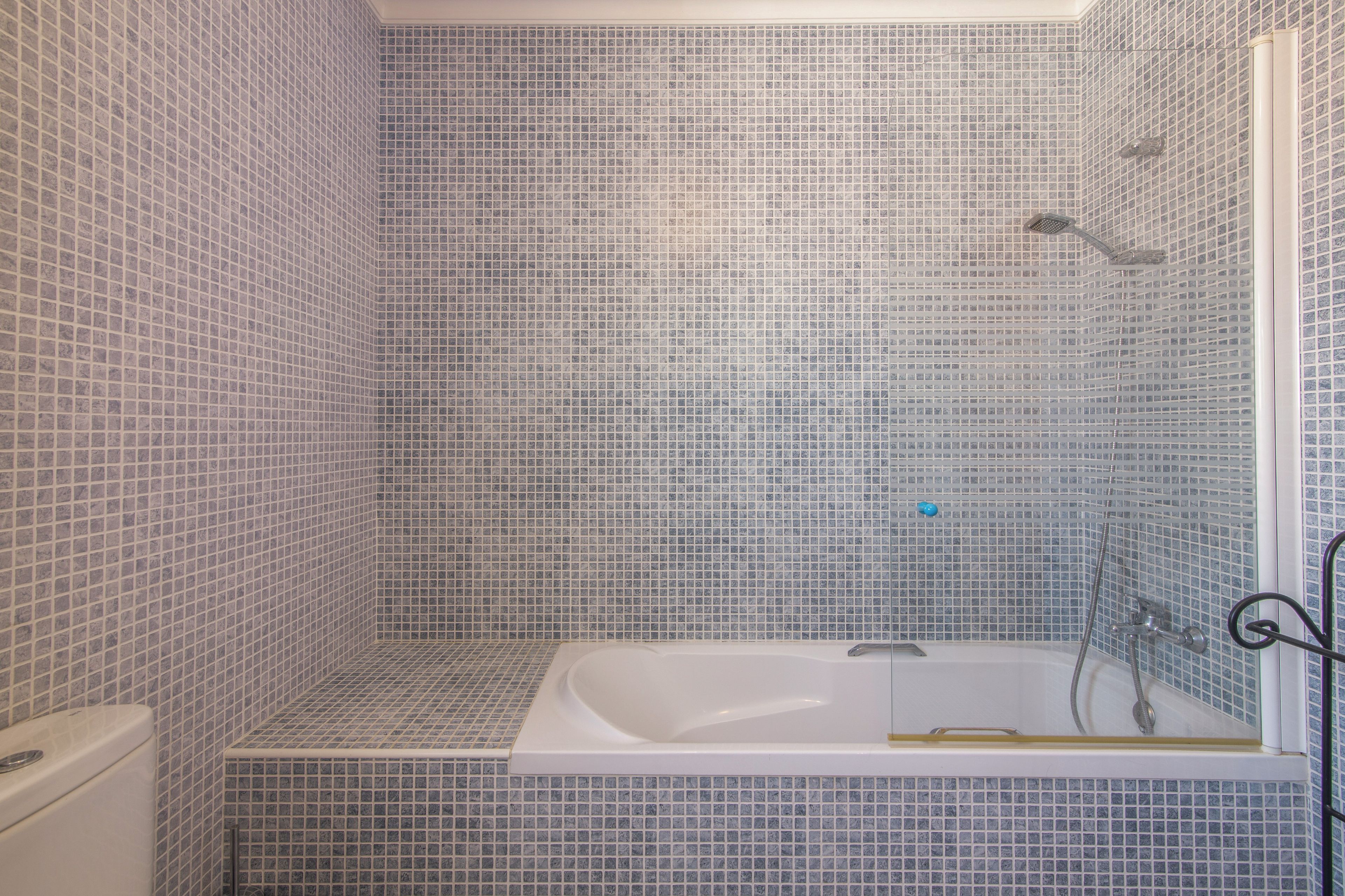 Ein Badezimmer mit Badewanne, Dusche und gefliesten Wänden.