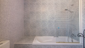 Ein Badezimmer mit Badewanne, Dusche und gefliesten Wänden.