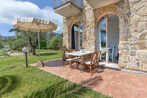 A stone building with a patio, outdoor table, chairs, and an umbrella. - Apartment 'Bilocale Castle' with Shared Pool, Wi-Fi and Air Conditioning (Campo nell'Elba)
