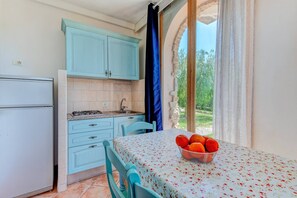 A kitchen with a refrigerator, stove, and sink, and a dining area with a table and chairs. - Apartment 'Bilocale Castle' with Shared Pool, Wi-Fi and Air Conditioning (Campo nell'Elba)