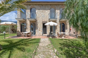 A stone building with balconies, outdoor seating, and a stone pathway. - Apartment 'Bilocale Castle' with Shared Pool, Wi-Fi and Air Conditioning (Campo nell'Elba)
