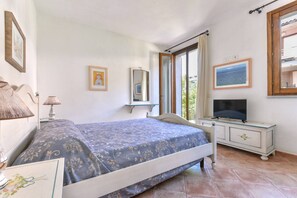 Une chambre à coucher avec un lit, une télévision, une commode, un miroir et une fenêtre.