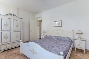 Een slaapkamer met een bed, een kledingkast, een nachtkastje en een lamp.