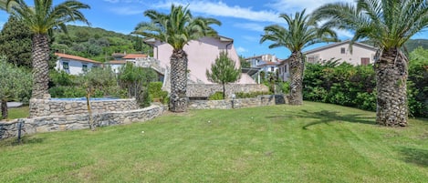 Un barrio residencial con muros de piedra, palmeras y casas con tejados rojos.