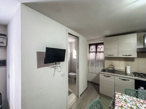 A compact kitchen with a built-in TV, a sink, and a stove. - I Rifugi dei Lucretili (Licenza)