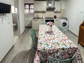 A compact kitchen with a dining area, a washing machine, and a sink. - I Rifugi dei Lucretili (Licenza)