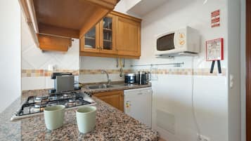 Une cuisine dotée de plans de travail en granit, d’une cuisinière à gaz, d’un four à micro-ondes et d’un lave-vaisselle.