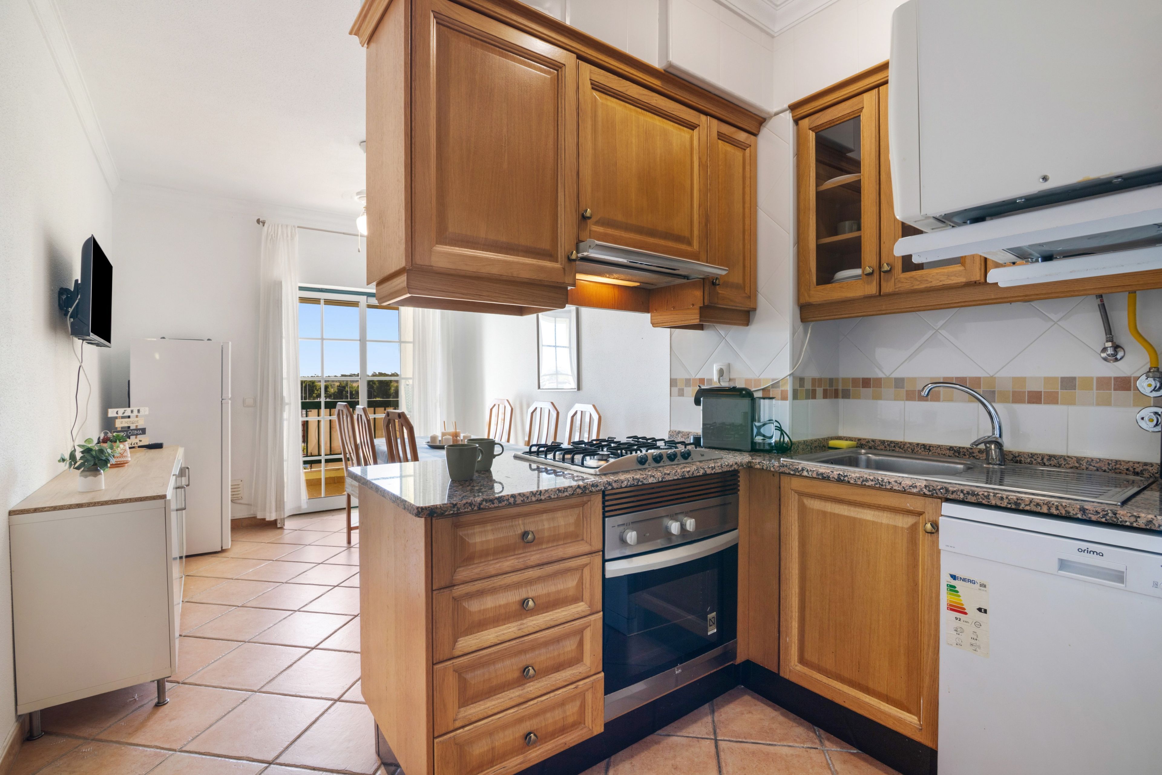 Une cuisine avec des meubles de rangement en bois, un four encastré, une cuisinière à gaz et un lave-vaisselle.