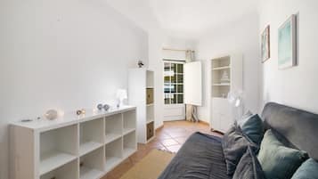 A modern living room with a grey sofa, white shelving unit, and a small table with decorative items.