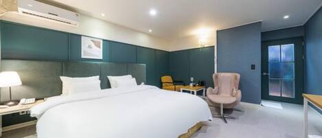 A hotel room with a large bed, a desk, a chair, and a door with frosted glass panels.
