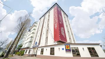 A tall hotel with a distinctive red patterned facade, a parking sign, and a clear sky.