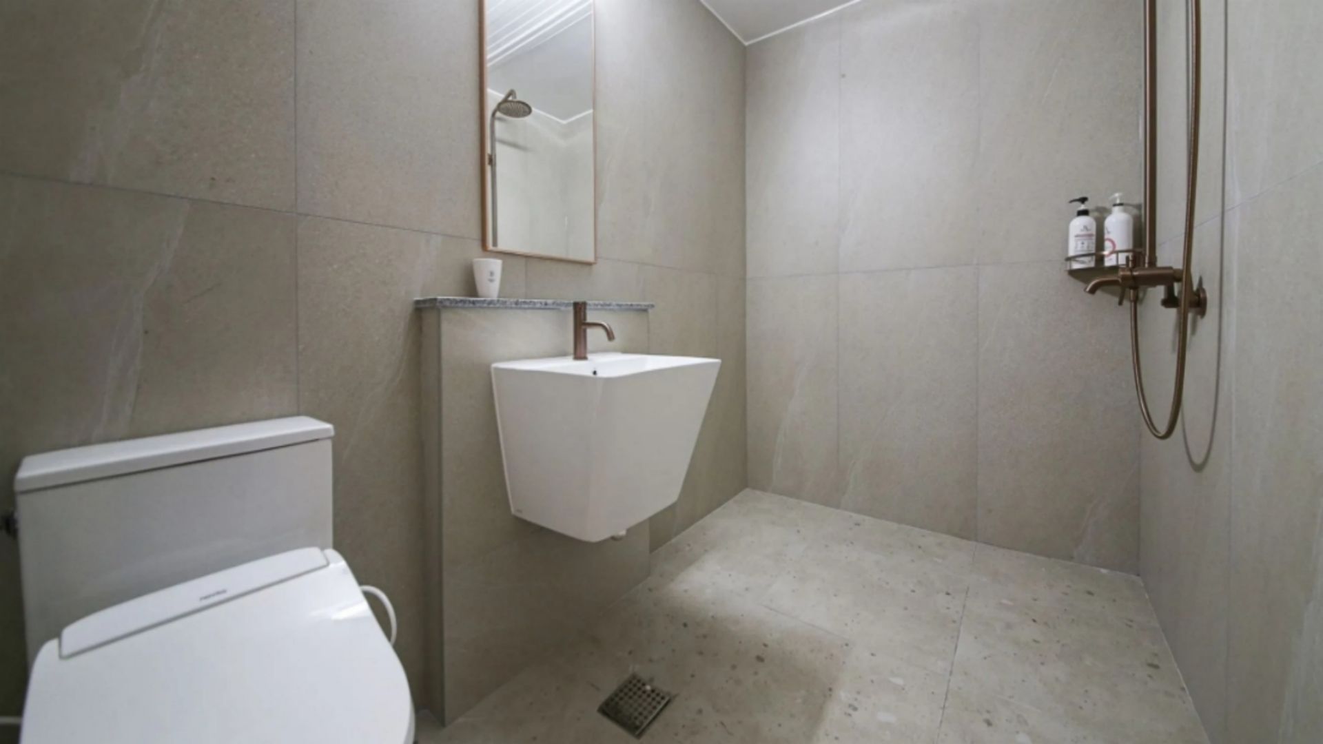 Een badkamer met toilet, wastafel, douche en spiegel.