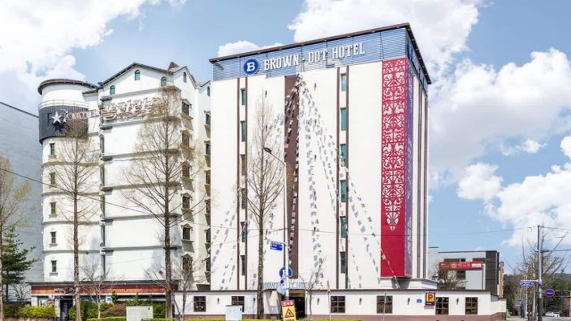 Een hotel met een opvallend bord, een cilindervormige constructie aan de linkerkant en een verticaal, rood designelement.