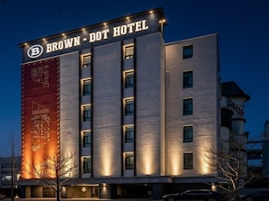 Un hotel de varios pisos con un cartel llamativo que dice 'BROWN DOT HOTEL'.