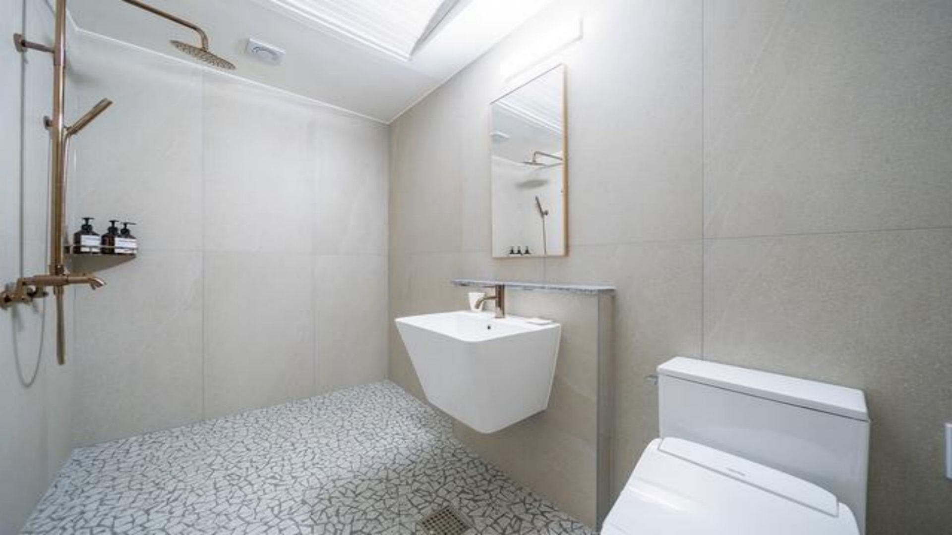 Un baño moderno con un lavabo blanco, inodoro y zona de ducha.