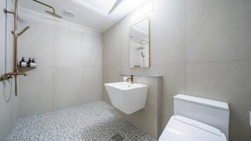 Un baño moderno con un lavabo blanco, inodoro y zona de ducha.