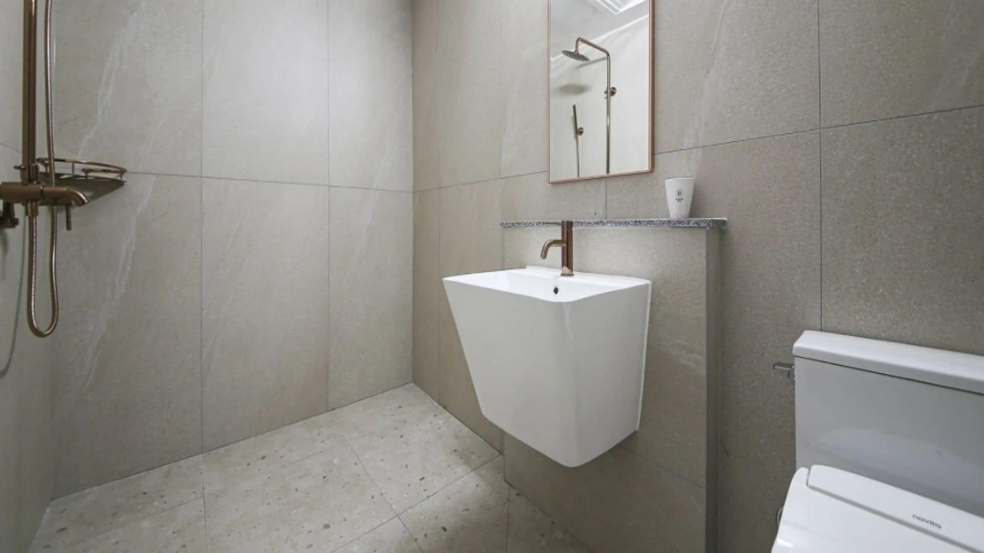 Un baño con un lavamanos blanco, un espejo y una ducha.