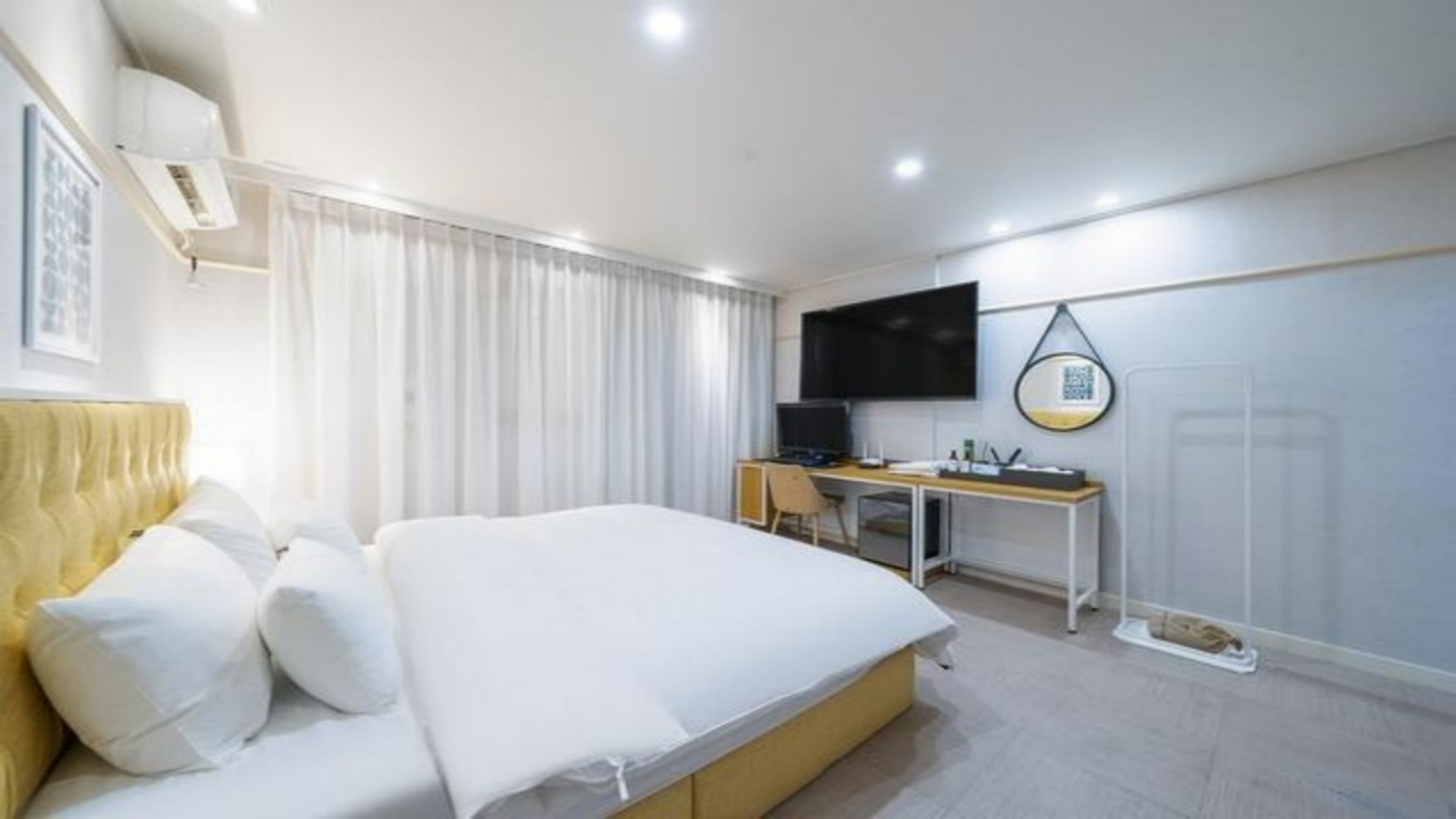 A hotel room with a bed, a desk, a television, and a window with curtains.