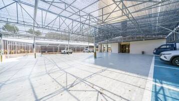 A spacious indoor parking area with a metal roof structure and a clear floor.