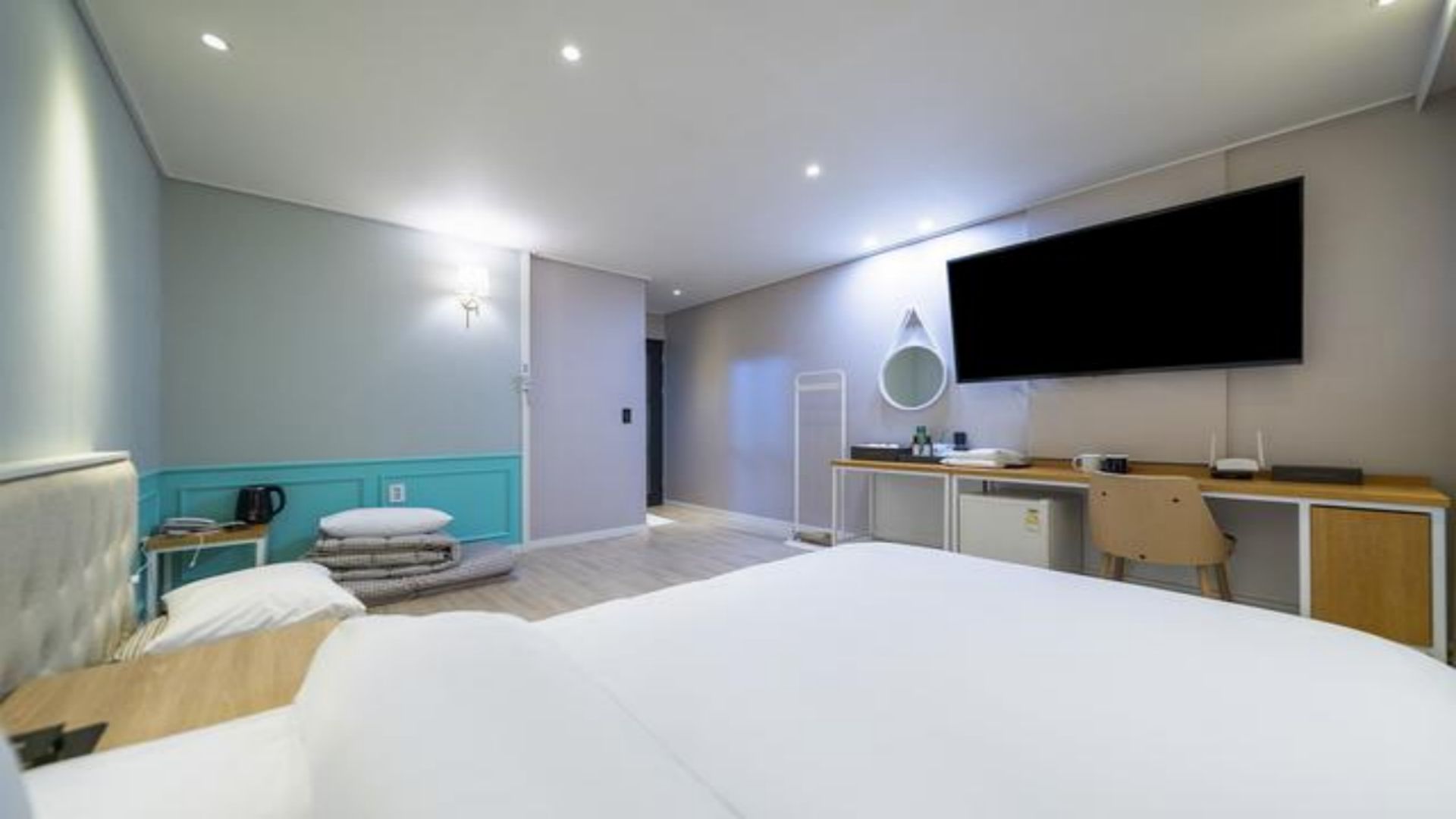 A modern hotel room with a large bed, a desk, a flat-screen TV, and a bathroom visible through an open door.