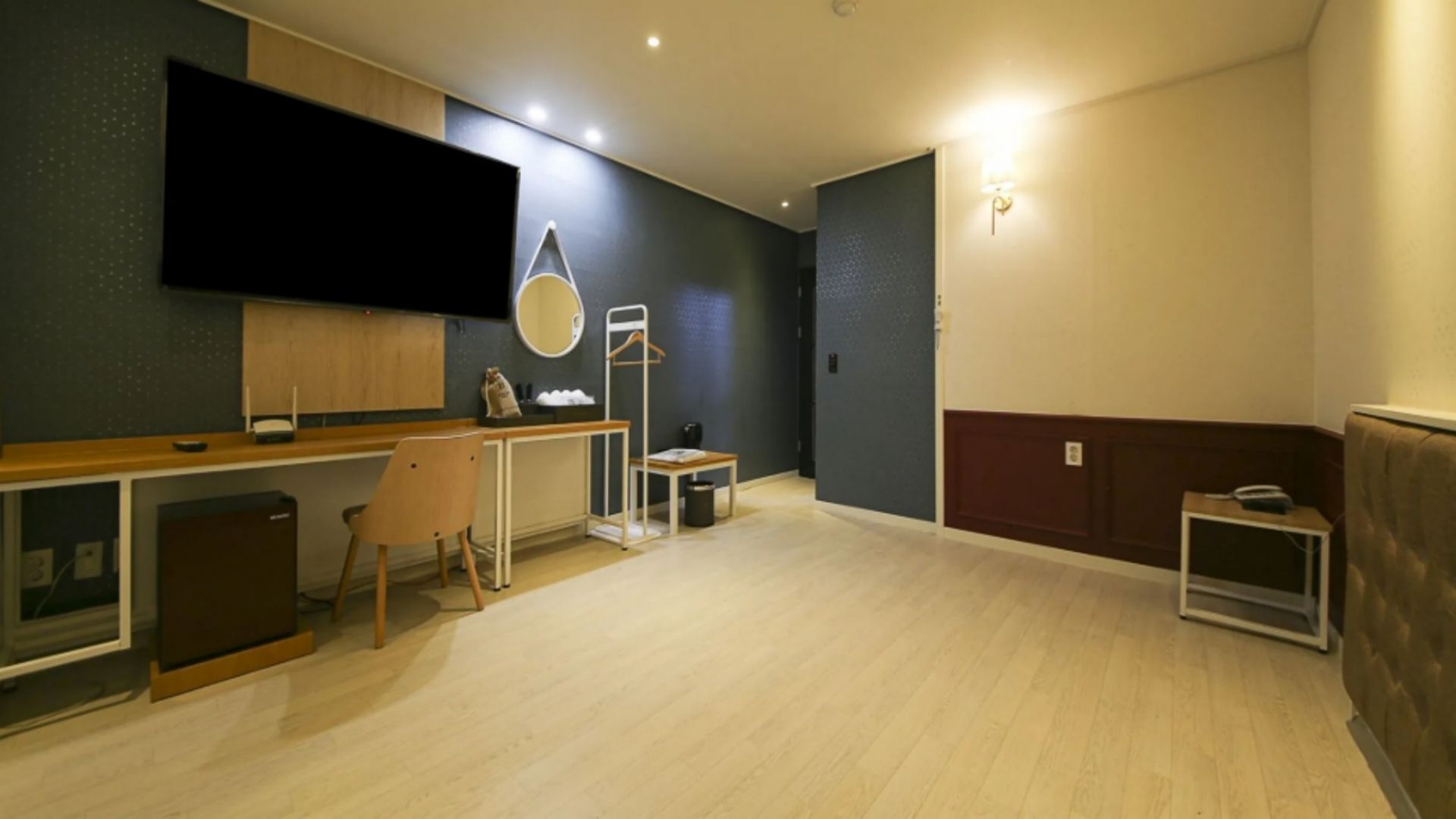 Ein modernes Wohnzimmer mit einem Flachbildfernseher, einem Holzessttisch, einem Stuhl und einem kleinen Beistelltisch.