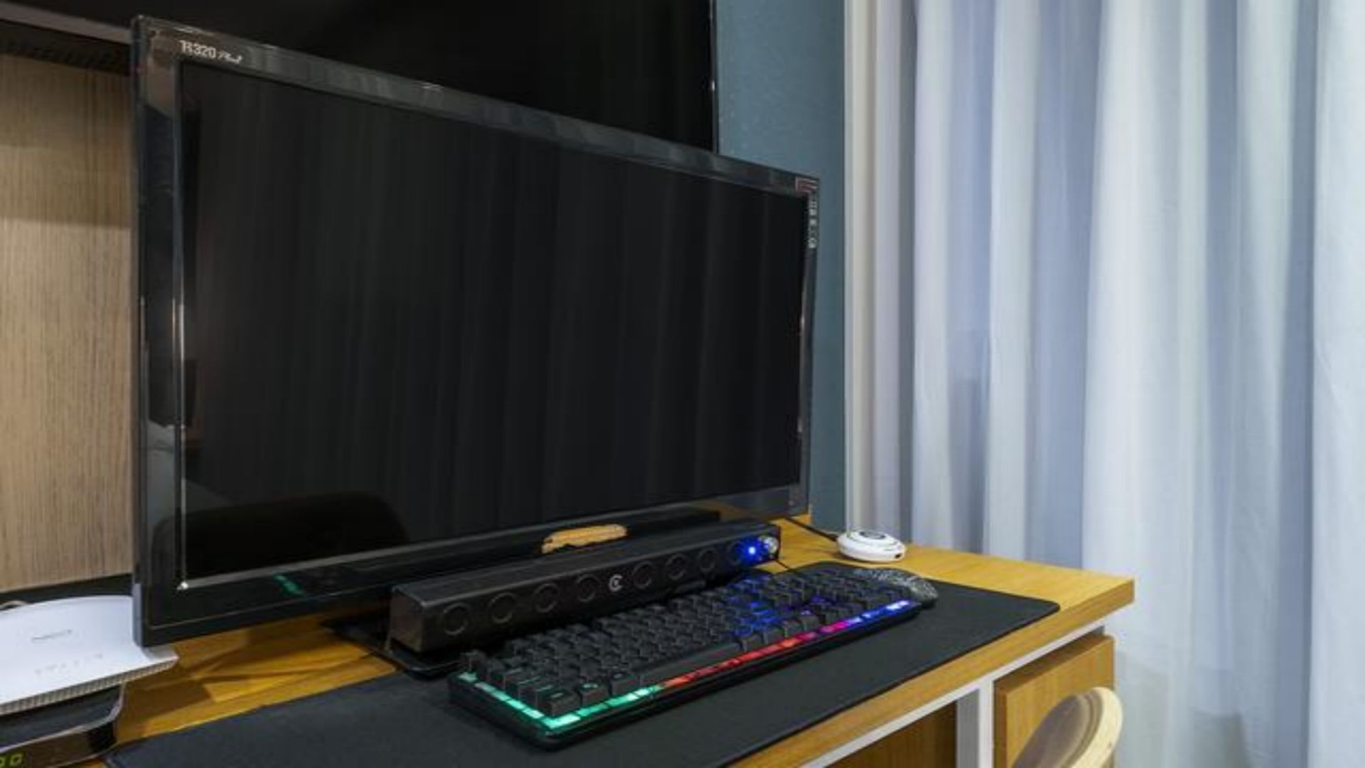 A gaming setup with a monitor, keyboard, and mouse on a wooden desk.