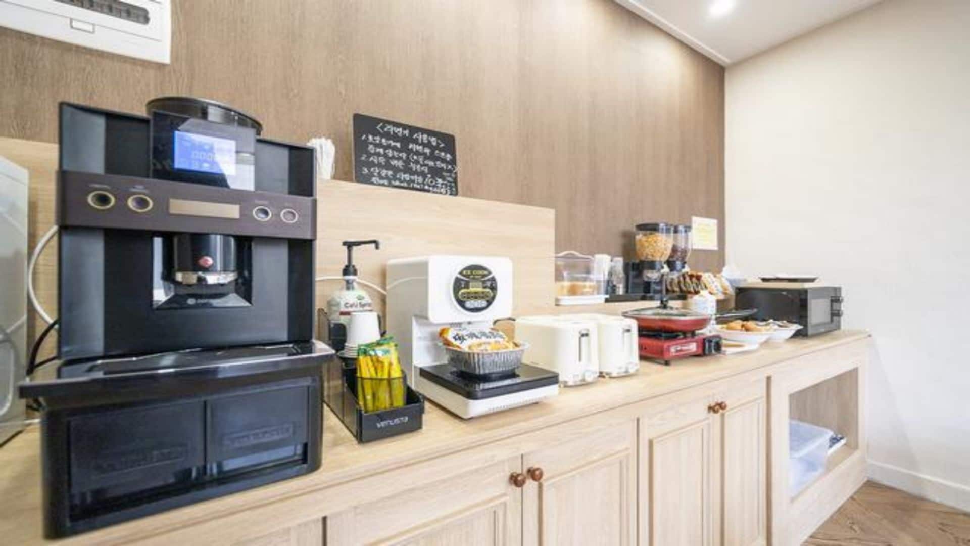 Una estación de café de autoservicio con una máquina de café, espumador de leche y un molinillo.