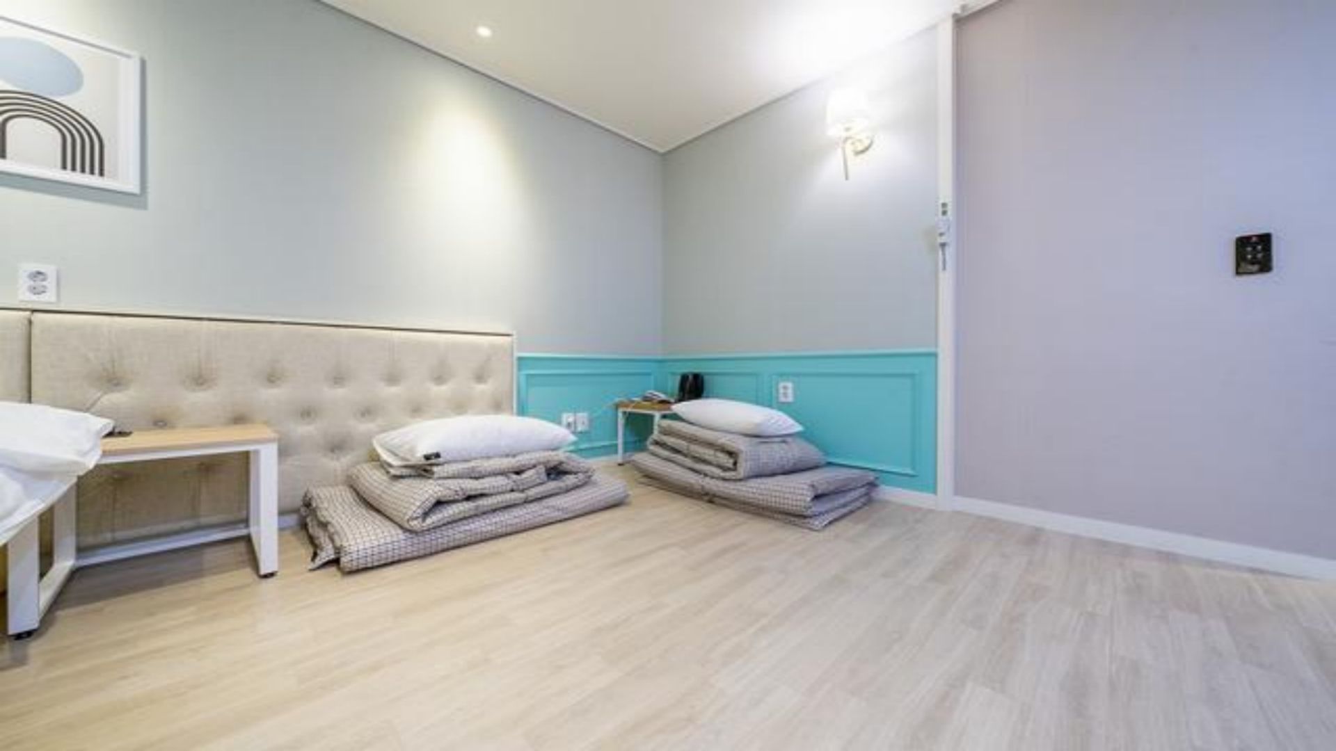 Una habitación de hotel con una cama, una mesita de noche, una lámpara y una luz empotrada en la pared.