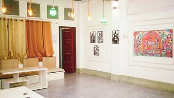 A room with a seating area, artwork on the walls, and a door leading to another space.