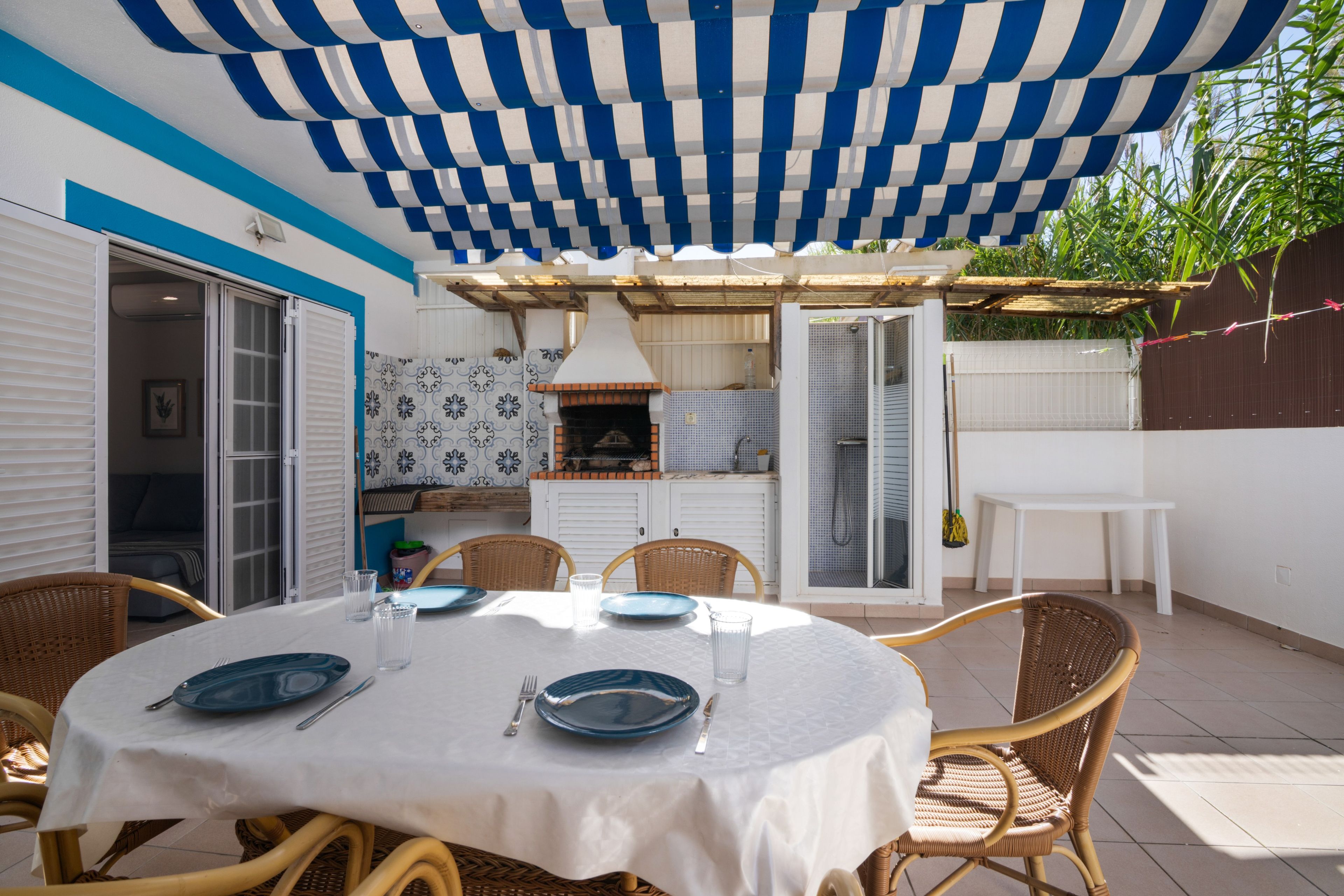 An outdoor patio with a round table set for dining, surrounded by wicker chairs.