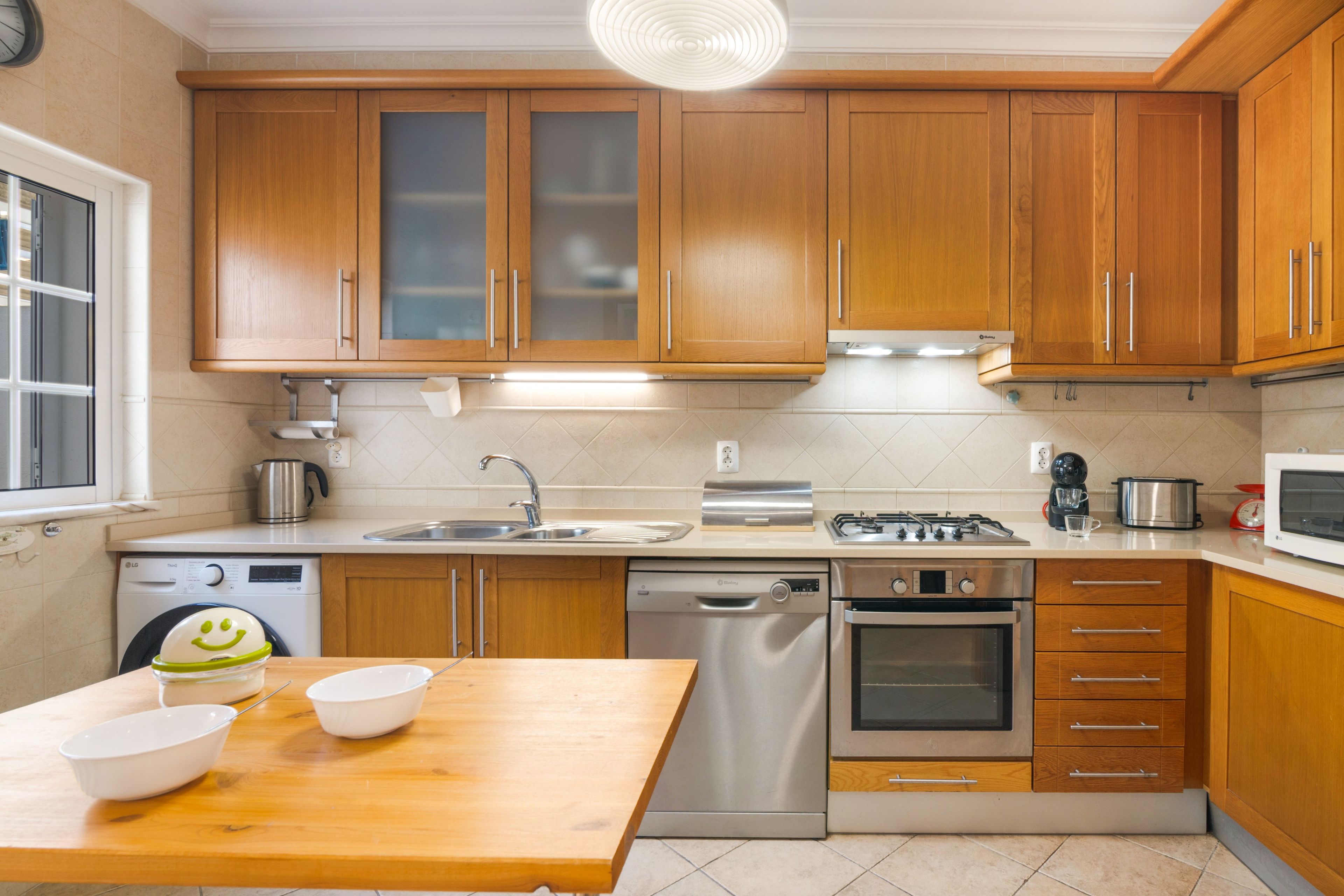 Una cocina moderna con armarios de madera, electrodomésticos de acero inoxidable y una mesa de comedor de madera.