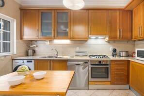 Une cuisine moderne avec des meubles en bois, des appareils électroménagers en acier inoxydable et une table à manger en bois.