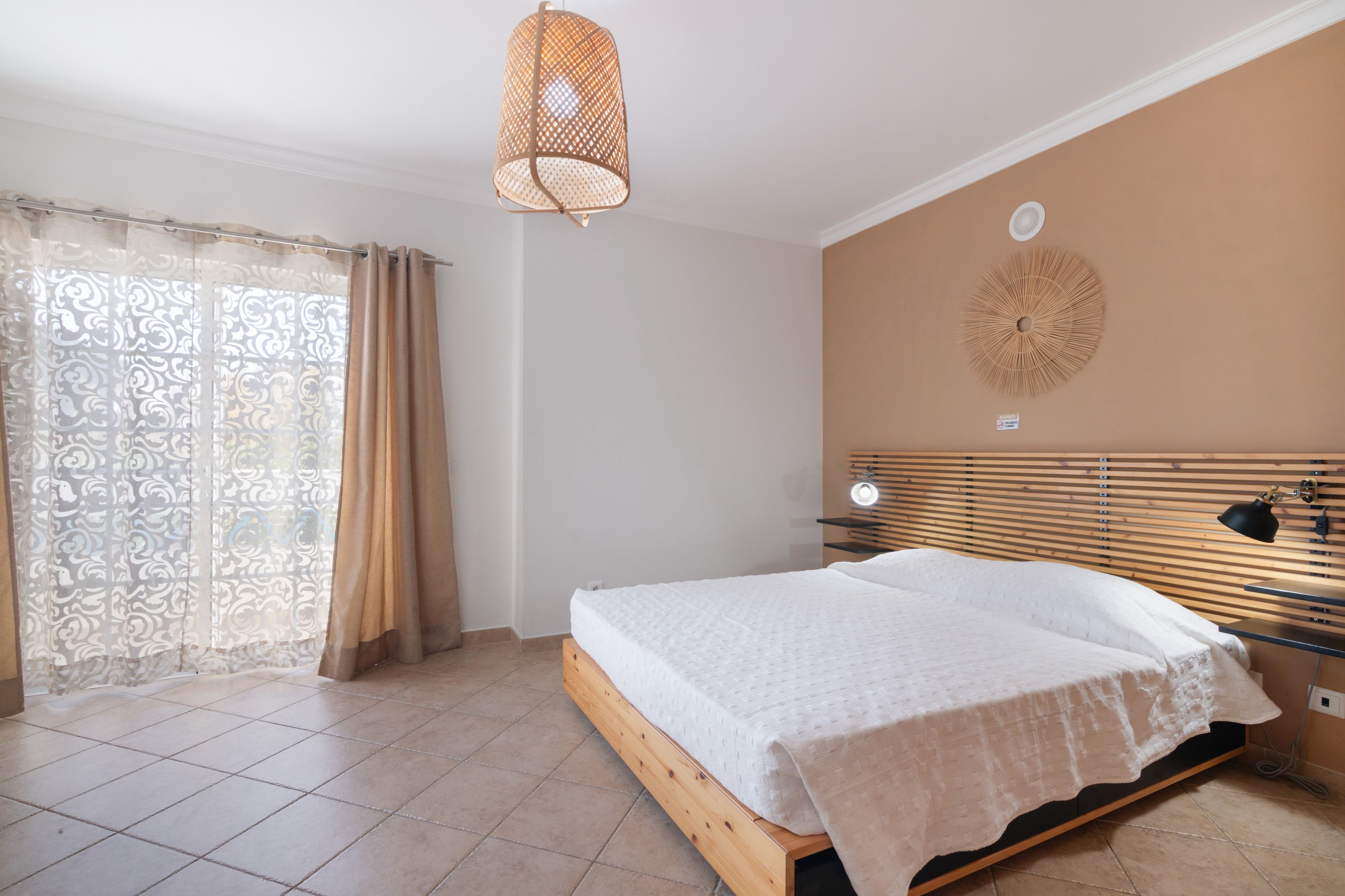 Une chambre à coucher comprenant un lit, un luminaire suspendu, une lampe fixée au mur et un élément décoratif mural.