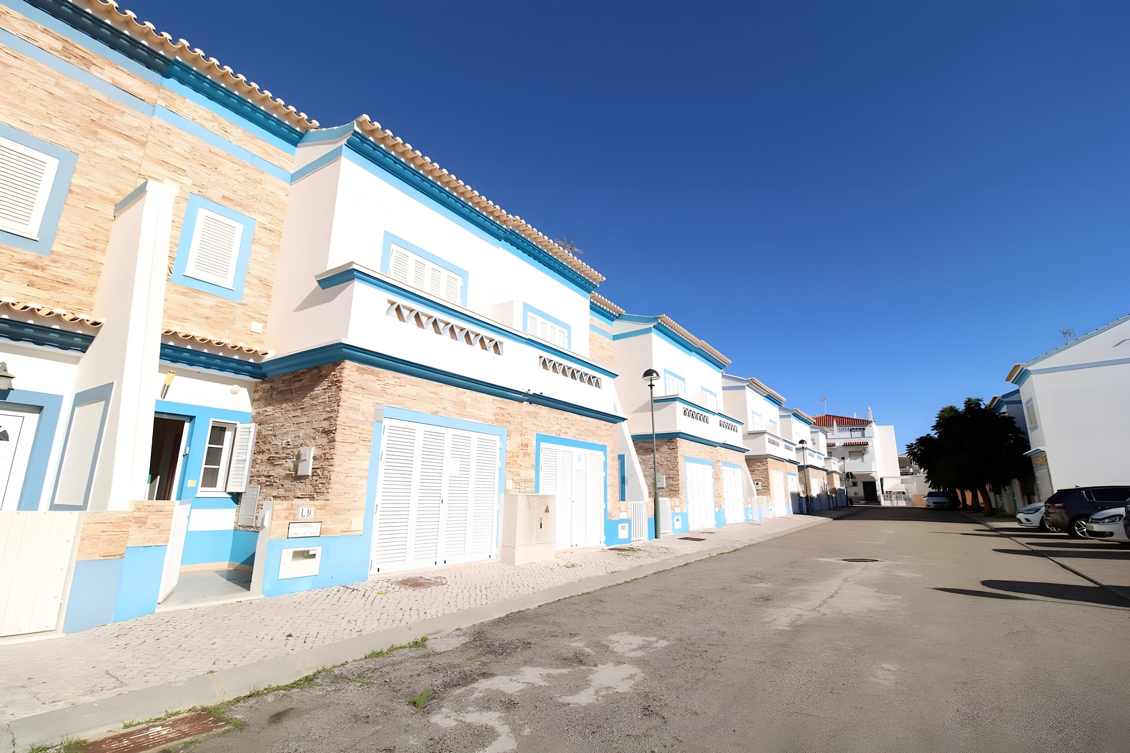Una hilera de edificios con fachadas azules y blancas, grandes puertas de garaje y un cielo despejado.