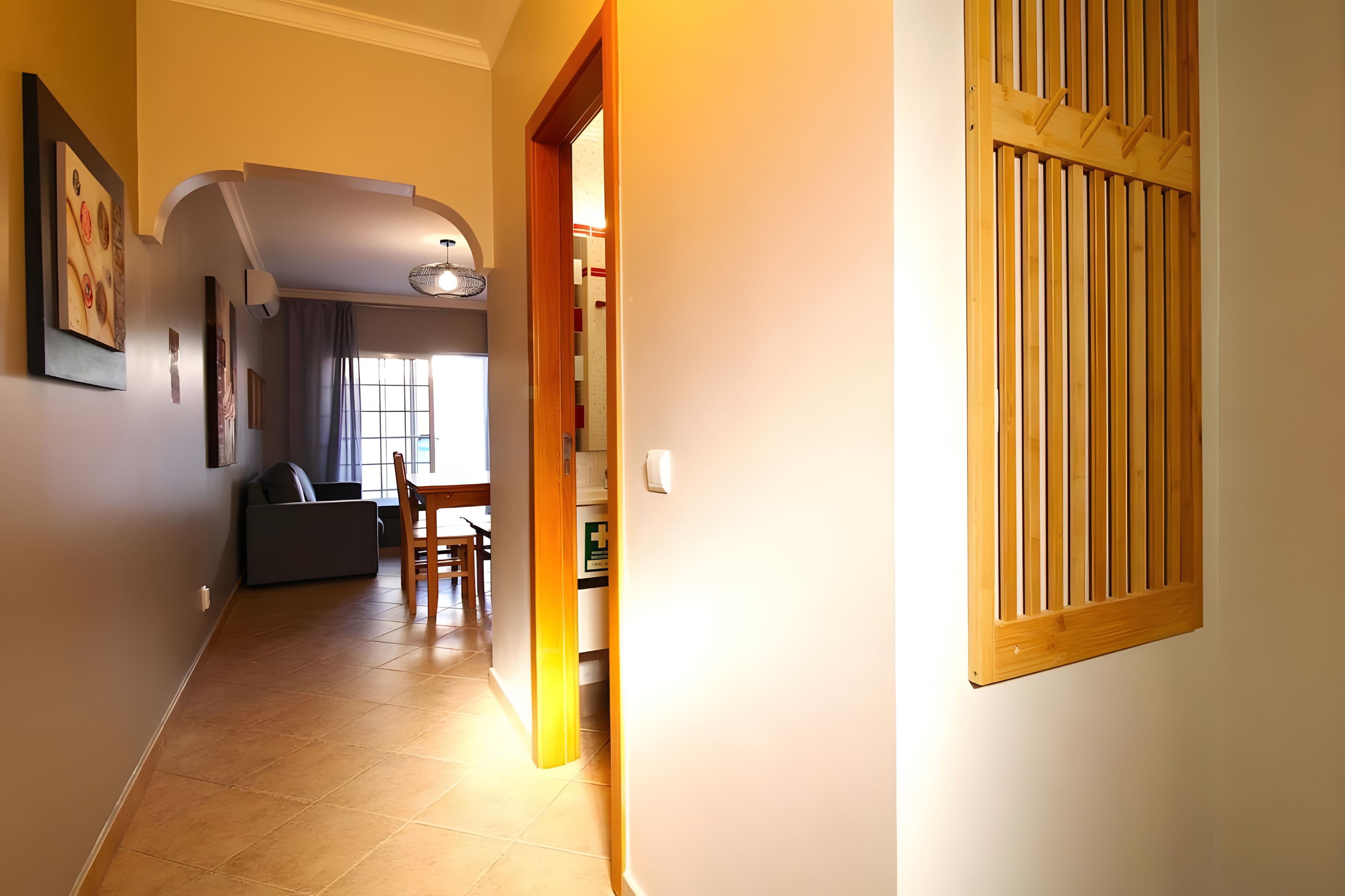 Un pasillo con zona de comedor, sofá y puerta de madera.