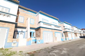 Una hilera de edificios con fachadas azules y blancas, varias puertas de garaje y un cielo despejado.