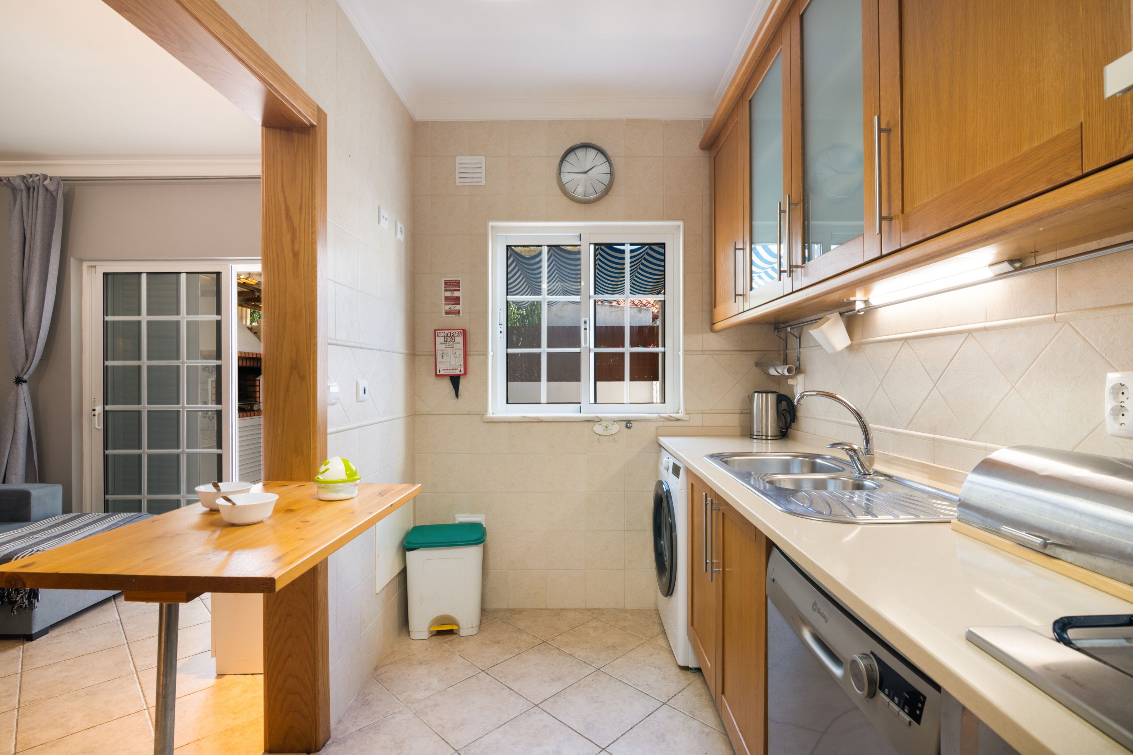Une petite cuisine équipée d’un lave-linge, d’un évier et d’une horloge murale.