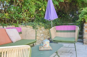 A wicker outdoor seating area with a table and a mug, surrounded by greenery. - Fabuleuse maison de campagne avec jardin proche Thoiry, Versailles (Auteuil)