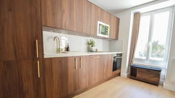 Une cuisine moderne avec des meubles en bois, un plan de travail blanc et un four à micro-ondes encastré.