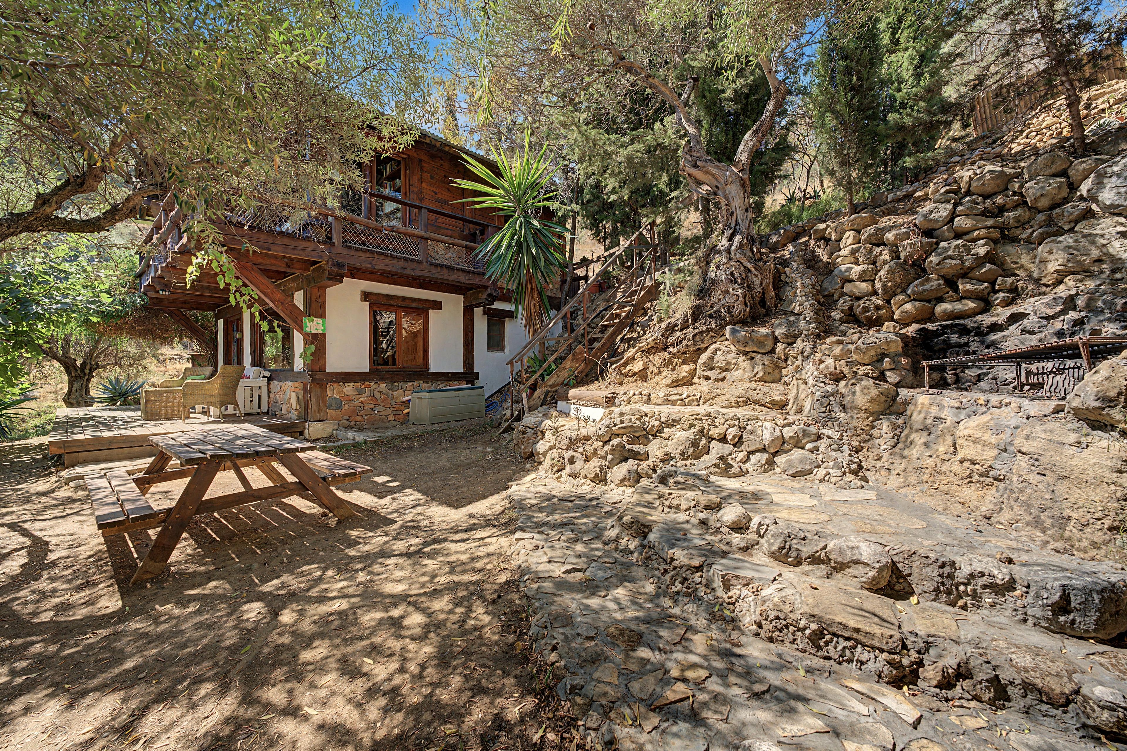 Un chalet rustique doté d’une terrasse en bois et d’un escalier en pierre.