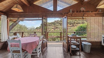 Una cabaña de madera con comedor, una mesa cubierta con mantel a cuadros y vistas del paisaje circundante.