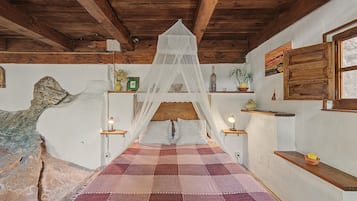 A room with a checkered floor, wooden beams, a bed with a canopy, bedside lamps, and a rustic wall.
