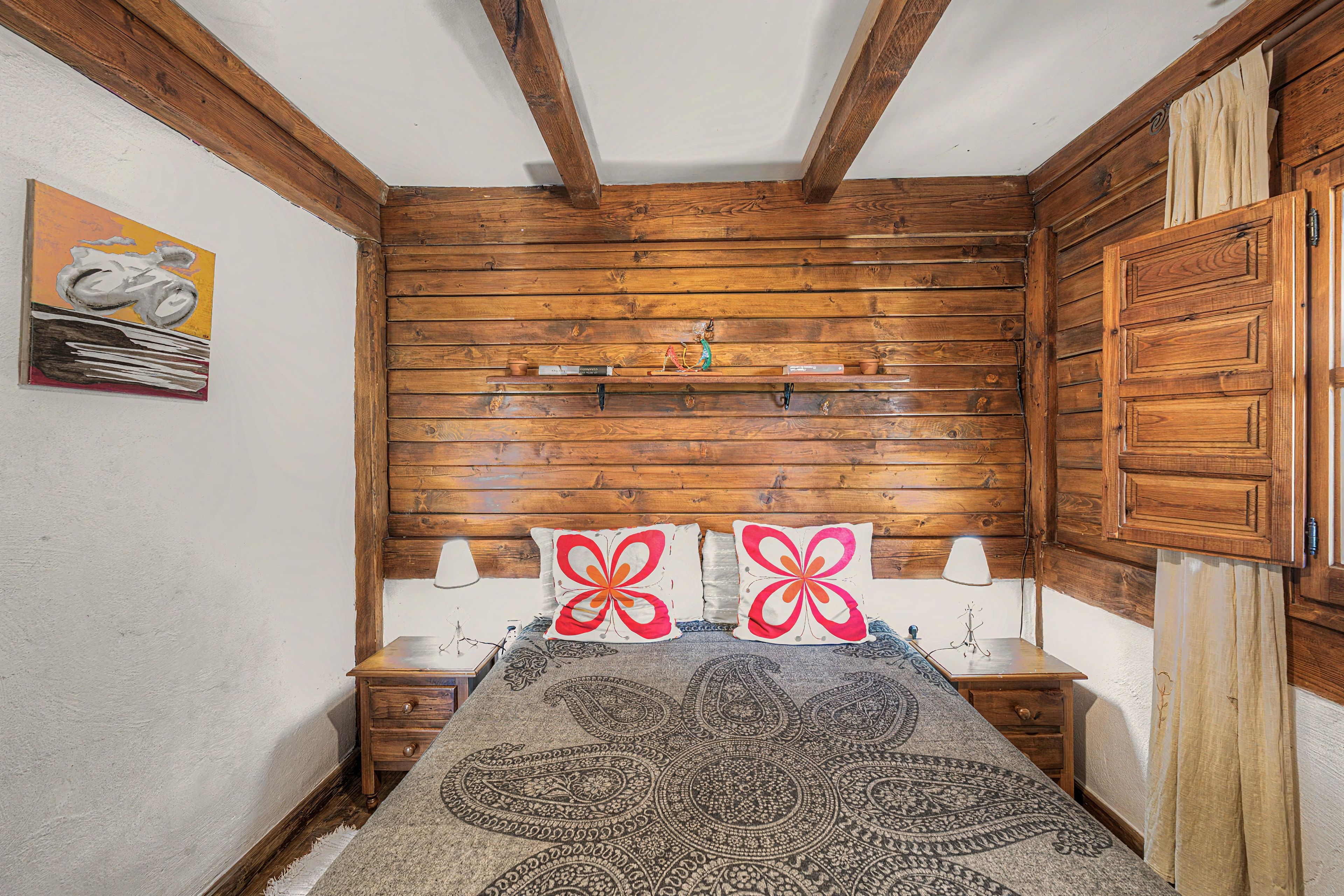 A room with wooden walls and a bed with patterned bedding.