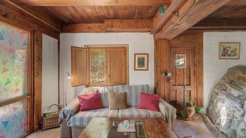 Una habitación acogedora con techo de madera, un sofá con cojines, una mesita de centro y una planta en maceta.