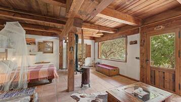Una habitación rústica de madera con una cama, una mesa con cubierta de vidrio y un ventanal grande.