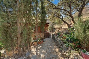 A stone pathway leading to a wooden cabin surrounded by coniferous trees.