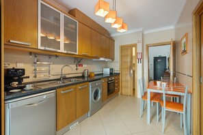 Une cuisine moderne avec des meubles en bois, un lave-vaisselle, un lave-linge et un coin repas comprenant une table et des chaises.